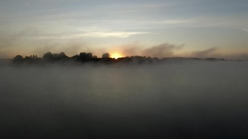 a misty sunrise over a lake with the sun in the background at Sodyba Brazylija in Taraldžiai