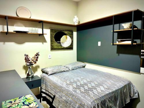 a bedroom with a bed and a table with a desk at CHARMOSO E BEM LOCALIZADO in Maracaju