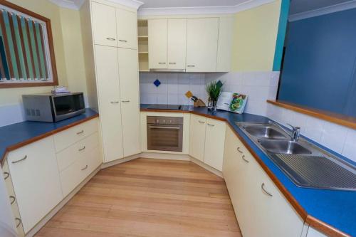a kitchen with white cabinets and a sink at McLeods - Three-Bedroom, Pet-Friendly Coastal Escape in Central Agnes Water in Agnes Water