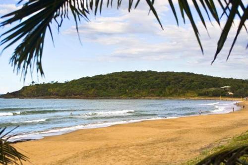 a beach with a bunch of people on the water at McLeods - Three-Bedroom, Pet-Friendly Coastal Escape in Central Agnes Water in Agnes Water