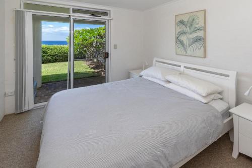 Dormitorio blanco con cama y vistas al océano en Blue Pacific, en Blueys Beach