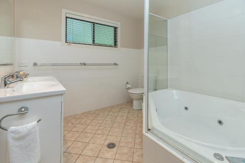 a bathroom with a tub and a sink and a toilet at A Yarraangunthi in Smiths Lake