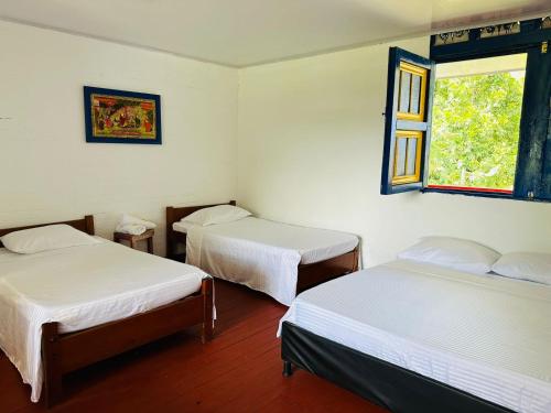 a room with two beds and a window at Finca Hotel el Edén del Quindío in Calarcá