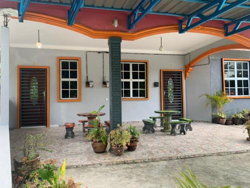 a patio with tables and benches and potted plants at Rerama Homestay Langkawi 5 minutes driving to Chenang Beach, kitchen, Wifi, parking, village vibes in Pantai Cenang