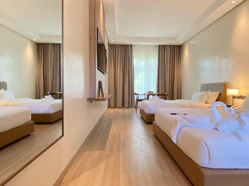 une chambre d'hôtel avec 3 lits avec des cygnes dans l'établissement Cocotree Resort, à Panglao