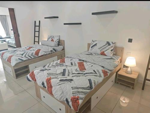 ein Schlafzimmer mit 2 Betten und einer Lampe auf dem Boden in der Unterkunft M-Residence in Pantai Cenang