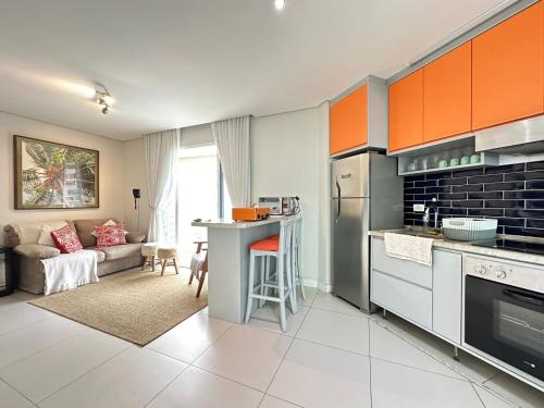 a kitchen with orange cabinets and a living room at Estanconfor 702 in Santos