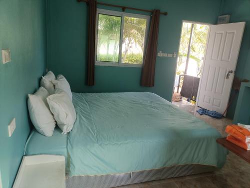 a blue bedroom with a bed with pillows and a window at Chill land house in Bang Tao Beach