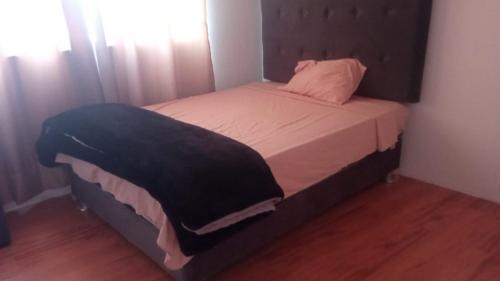 ein kleines Schlafzimmer mit einem Bett mit einem schwarzen Kopfteil in der Unterkunft Hospedaje sol y sombra in Pisco