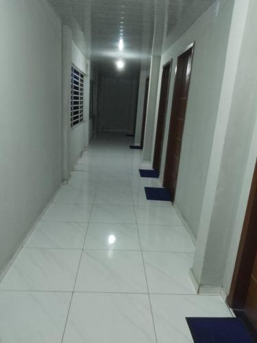 a long hallway with white floors and blue stairs at HOTEL NOVAES in Castanhal