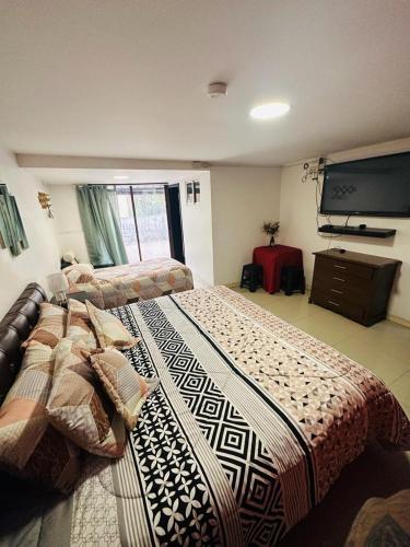 a bedroom with a large bed and a flat screen tv at HOTEL VIEILLE MAISON in Quito