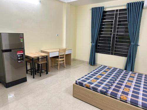 Zimmer mit einem Bett, einem Tisch und einem Kühlschrank in der Unterkunft nhatro19nguyenkhang in Hanoi