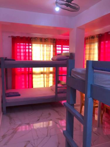 um quarto com 2 beliches e cortinas vermelhas em Jirah’s inn em Legazpi