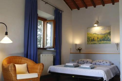 ein Schlafzimmer mit einem Bett mit blauen Vorhängen und einem Stuhl in der Unterkunft Podere Massoli in San Casciano in Val di Pesa
