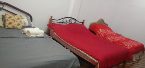łóżko z czerwonym kocem na górze w obiekcie Melrose homestay and transport w mieście Kampong Parit