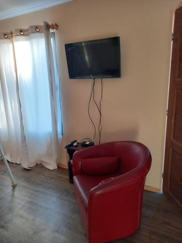 sala de estar con silla roja y TV de pantalla plana en Cabaña Encantos del Mar, en Cáhuil