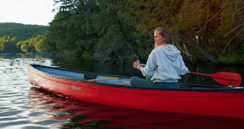 a young girl is rowing a red boat on the water at Bonnie View Inn in Haliburton