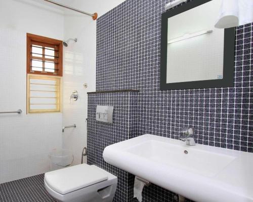 a bathroom with a white sink and a toilet at ZIONS APERTMENT in Yelahanka