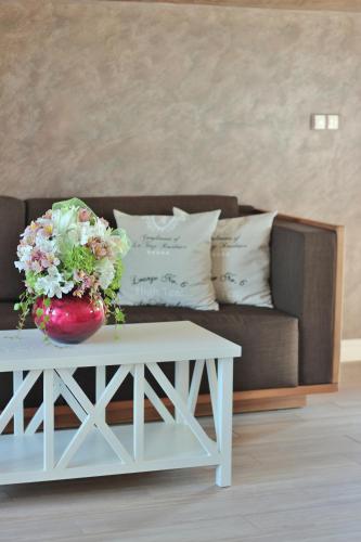 a white coffee table with a vase of flowers on a couch at Residence House Ruse in Ruse