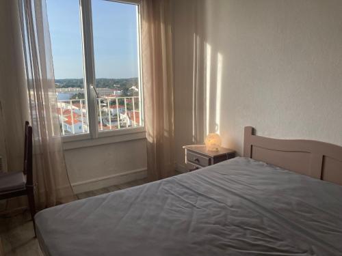 une chambre avec un lit et une grande fenêtre dans l'établissement Appartement 2 chambres avec Wi-Fi, vue mer, proche plage à Saint-Jean-de-Monts - FR-1-323-136, à Saint-Jean-de-Monts