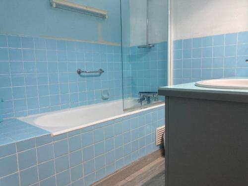 La salle de bains est pourvue de carrelage bleu, d'une baignoire et d'un lavabo. dans l'établissement Appartement 2 chambres avec Wi-Fi, vue mer, proche plage à Saint-Jean-de-Monts - FR-1-323-136, à Saint-Jean-de-Monts