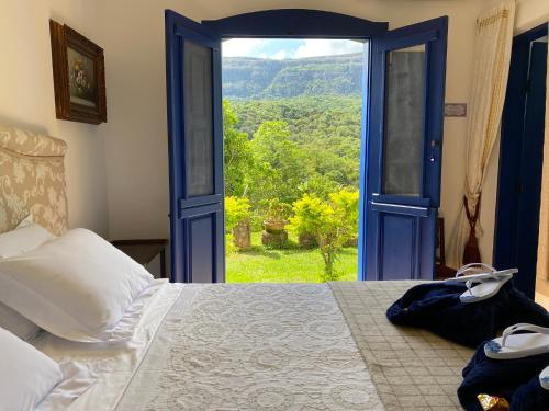 a bedroom with a bed and an open door at Segredo da Serra Guest House in Tiradentes