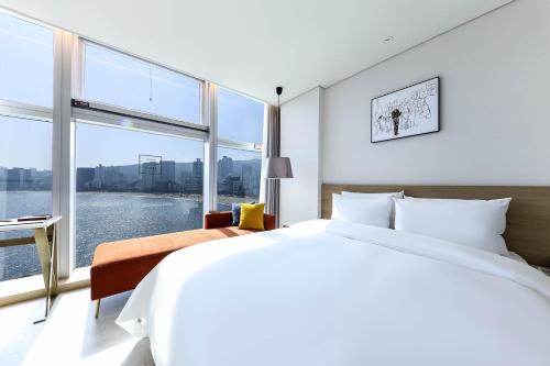 een slaapkamer met een groot bed en een groot raam bij Ocean 2 Heaven Hotel in Busan