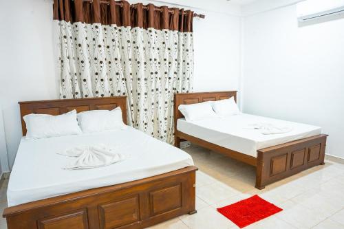 dos camas sentadas una al lado de la otra en un dormitorio en Elegant Riverside Villa, en Dematapelessa