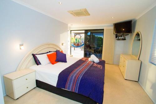 a bedroom with a bed and a television in it at Moorings - Beach house with pool in beautiful 1770 in Seventeen Seventy