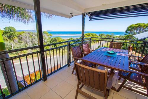 a table and chairs on a balcony with a view of the ocean at Moorings - Beach house with pool in beautiful 1770 in Seventeen Seventy