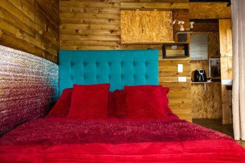 een rood bed met een blauw hoofdeinde en rode kussens bij Cabaña San Angel in La Ceja