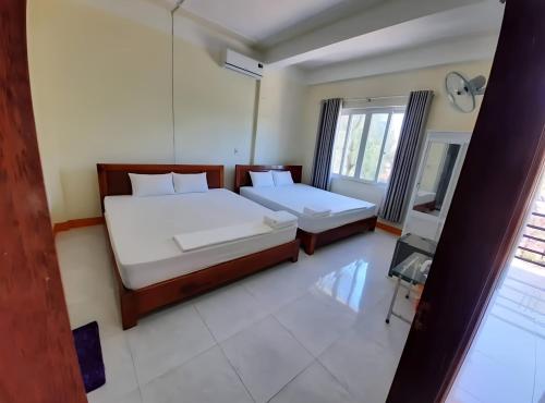 a bedroom with two beds and a window at View Nhat Le Beach Hotel in Dong Hoi