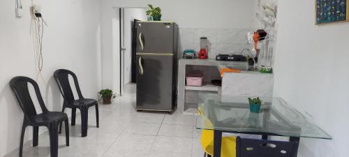a kitchen with two black chairs and a refrigerator at Apartahotel in Taganga