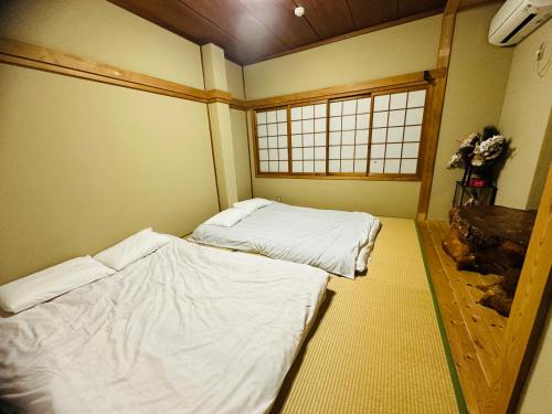 zwei Betten in einem kleinen Zimmer mit Fenster in der Unterkunft Rest collection Nayacho Kyoto in Kyoto