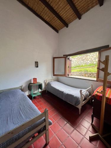 1 dormitorio con 2 camas y ventana en La Ramada en Tafí del Valle