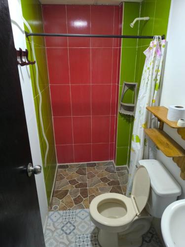 a bathroom with a toilet and green and red tiles at Hotel Palmetto Beach Coveñas in Coveñas