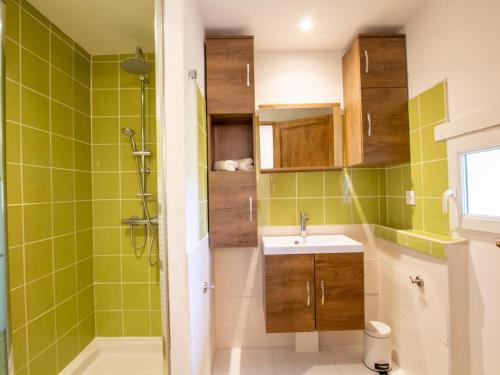La salle de bains est pourvue de carrelage vert, d'un lavabo et d'une douche. dans l'établissement Gîte cosy avec jacuzzi privé, jardin clos, et équipements modernes au cœur du Périgord pourpre - FR-1-616-363, à Saint-Aubin-de-Lanquais