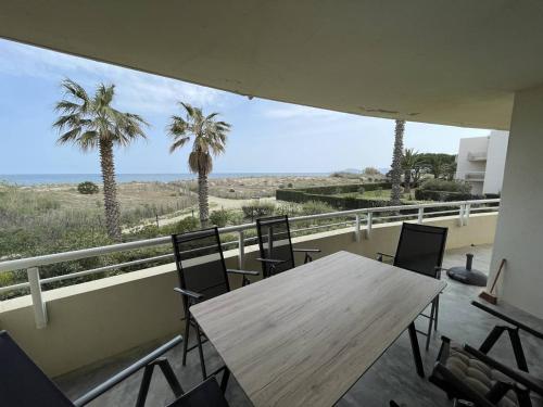 d'une table et de chaises sur un balcon avec des palmiers. dans l'établissement T3 6 pers avec piscine et accès direct plage - Saint-Cyprien - FR-1-106-101, à Saint-Cyprien