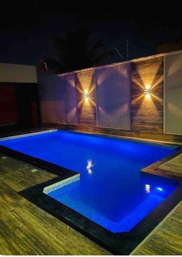 a blue swimming pool at night with lights on the wall at Casa piscina 3 quartos in Goiânia