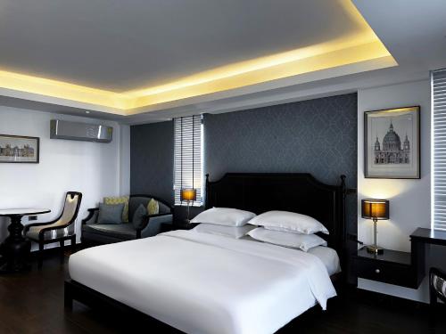una camera con un grande letto bianco e una sedia di Glory Boutique Suites 清迈古城荣耀精品酒店 a Chiang Mai