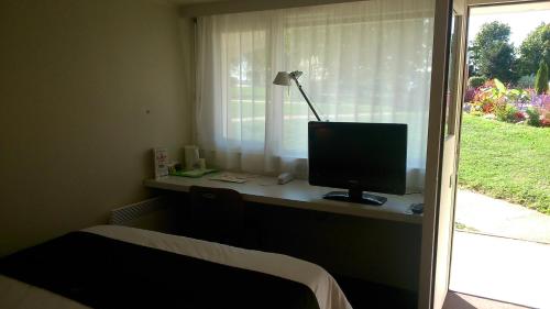 a room with a desk with a computer on a window at Hotel Campanile Besançon Nord Ecole Valentin in Besançon