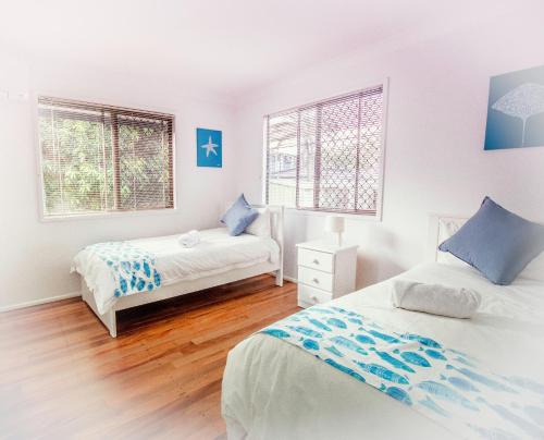 1 dormitorio con 2 camas y 2 ventanas en Holiday House, en Brisbane