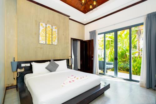 ein Schlafzimmer mit einem großen weißen Bett und einem großen Fenster in der Unterkunft Angkor Tempora Boutique in Siem Reap