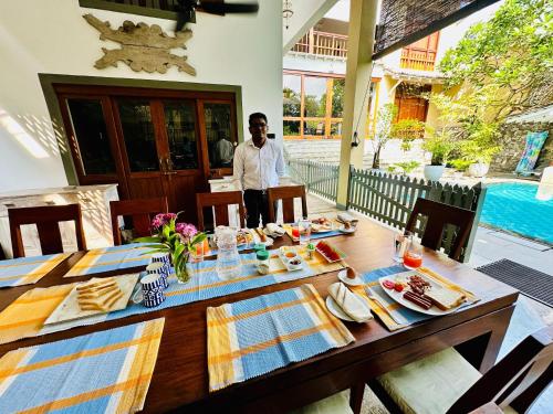 a man standing in front of a table with food on it at Colonial Retreat Villa in Talawatugoda