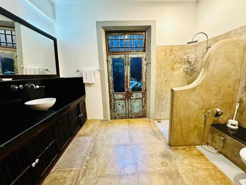 a bathroom with a sink and a mirror and a door at Colonial Retreat Villa in Talawatugoda