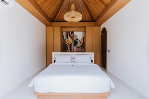 een slaapkamer met een wit bed en een houten plafond bij Vella Villa by Mai Bali Hospitality in Canggu