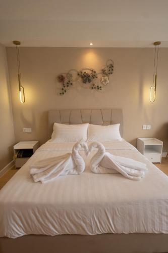a bed with two heart shaped towels on it at White Roses Cottage in Keningau
