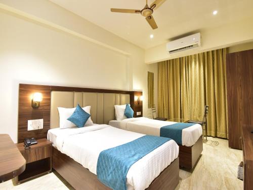 a hotel room with two beds and a television at Hotel Candor Amigo Airoli Mind Space in Navi Mumbai