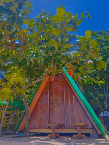 una pequeña casa con un árbol delante en Coolis beach, en Masbate