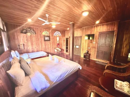 - un grand lit dans une chambre dotée de murs en bois dans l'établissement XiengThong KhounPhet GuestHouse, à Luang Prabang
